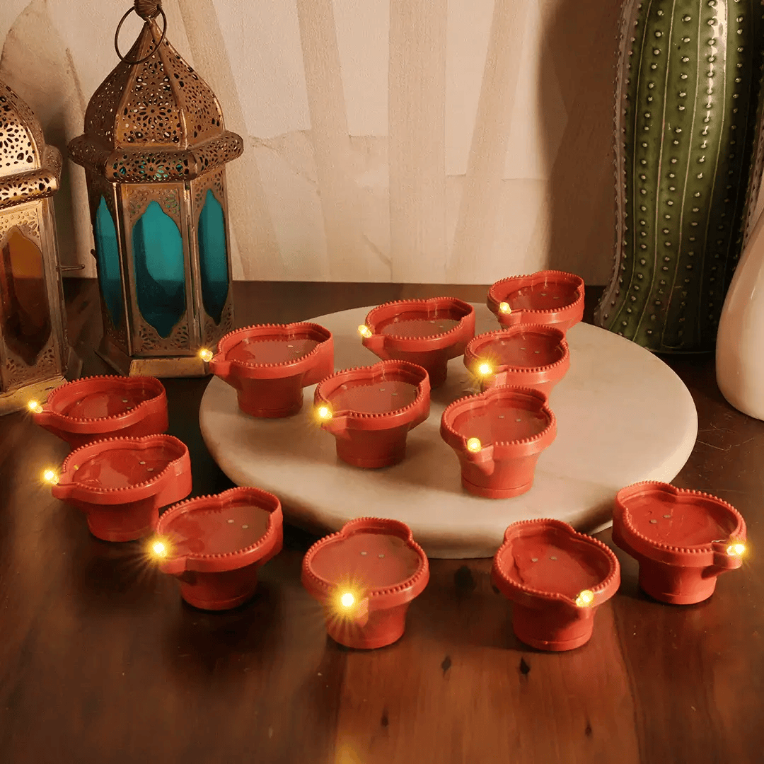Water Sensor LED Diya collection glowing on a decorative table with lanterns and plants.